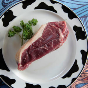 Grass-fed New York strip steak on a white plate.